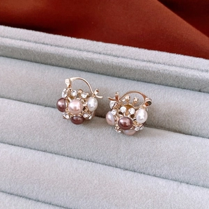 Detailed macro view of gold earrings with clustered colorful pearls and shiny rhinestones