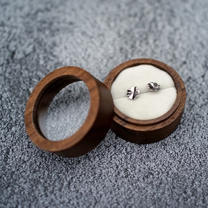 Detailed view of silver clover earrings in a walnut wood jewelry box with window