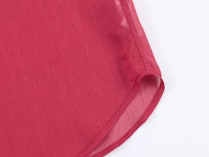 Détail de l'ourlet incurvé de la chemise en mousseline rouge foncé avec coutures fines