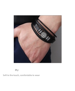 Macro detail of men's layered leather bracelet with a Nordic Viking compass charm