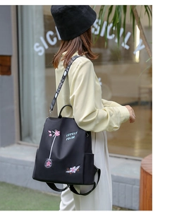 Detailansicht der rosa Blumenstickerei und des Jacquard-Gurtes am schwarzen Nylon-Rucksack