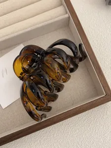 Close-up of tortoise shell resin hair claw clip in a wooden storage box with linen lining