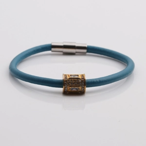Bracelet en cuir bleu avec cylindre doré serti de zircons et fermoir magnétique argenté