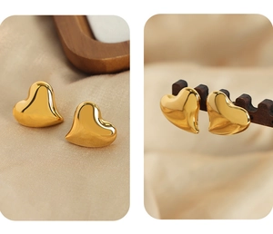 Detail view of gold heart earrings on beige silk and dark wooden display stand