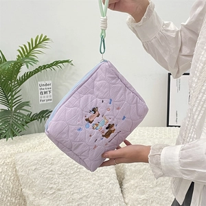 Detailed view of lavender quilted toiletry bag with cute dog embroidery and green strap