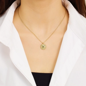 Détail du collier pendentif soleil plaqué or 18k avec pierres vertes sur un mannequin