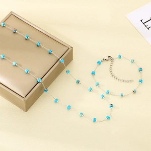 Adjustable silver chain jewelry set with blue and brown glass beads on a gift box