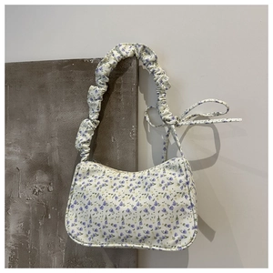 Detail of floral tote bag with purple prints, featuring a pleated strap and zip closure