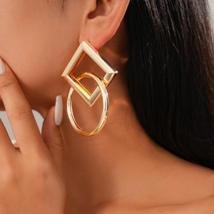 Close-up of a model wearing gold geometric earrings with interlocking square and circle