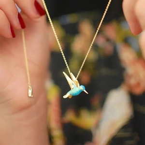 Close-up of a blue gradient hummingbird pendant necklace with a delicate gold chain