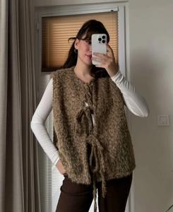 Detail view of brown fluffy vest with tie closure and soft plush texture for women