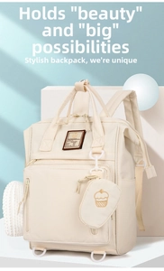 Detail view of cream-white waterproof mommy backpack with cute cupcake charm and large capacity