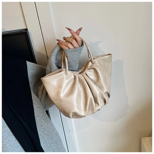 Detail shot of beige ruched cloud tote featuring soft leather texture and elegant handles
