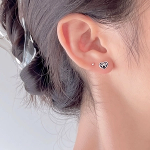 Minimalist 925 sterling silver heart bow earrings with black enamel on model ear