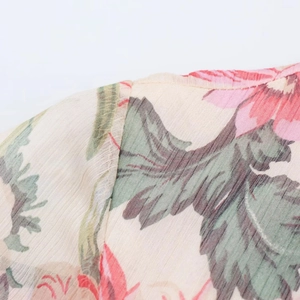 Detailed close-up of pink floral chiffon fabric with quality stitching on the shoulder seam