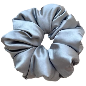Detail view of large light blue satin scrunchie with soft pleated texture and silky shine