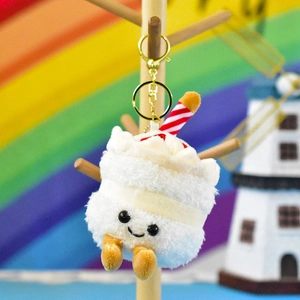 Detailed view of white fluffy cake plush keychain with a candle and smiley face