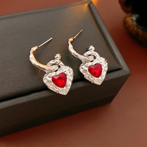 Detail of silver heart earrings featuring a vintage textured red heart gemstone