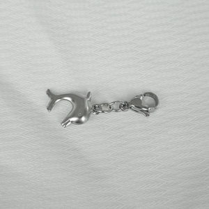 Polished stainless steel dolphin pendant with a lobster clasp on a grey fabric texture