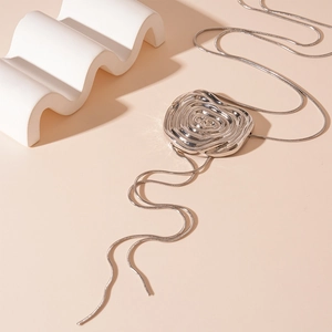 Détail du pendentif rose argenté et chaîne serpent sur fond géométrique beige