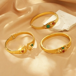 Detailed view of three vintage gold geometric bracelets with red and green gemstones