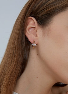 Detail of gold leaf earrings with marquise-cut zircon stones worn by a model