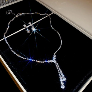 Detailed view of silver Y-shaped necklace and teardrop earrings with crystals in a black box