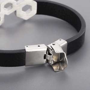 Braided black leather cord bracelet with stainless steel buckle on a grey background