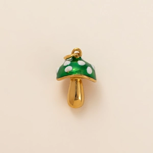 Macro detail of mushroom charm with green enamel and white spots in 18k gold plating