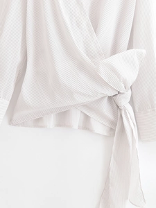 Detail of a white grey striped wrap shirt featuring a large waist bow and tied side knot