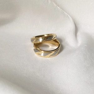 Minimalist gold and silver titanium steel couple rings with twill pattern on white silk