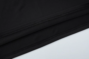 Detail view of the black dress hemline showing high-quality stitching and fabric texture