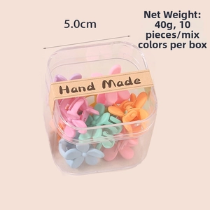 Detailed view of 10 mini flower hair claws in a box with Hand Made sealing label