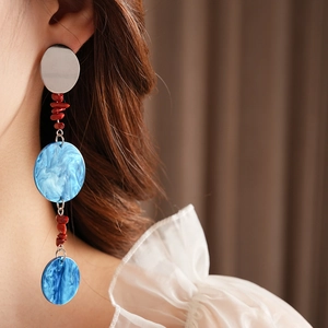 Close-up of long tassel earrings with silver sequins, red beads and blue marble discs