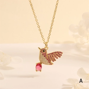 Macro shot of gold hummingbird pendant with red gemstones and crystals on dry flower petals