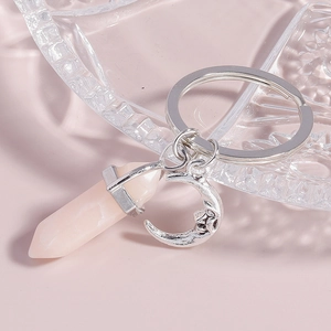 Detailed shot of pink hexagonal crystal prism and silver smiling moon keychain on glass deco