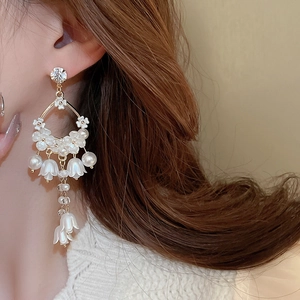 Close-up of elegant lily of the valley earrings with white flowers and pearl tassels