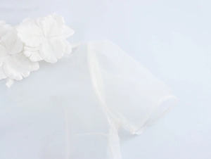 Close-up of white organza top featuring elegant 3D floral embellishments on the shoulder