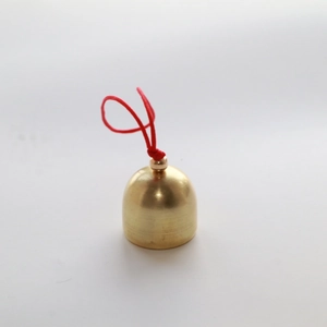 Close-up of 2cm brass Christmas bell with red hanging string on a grey background