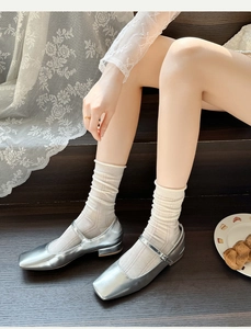 Scarpe Mary Jane argentate con calze a rete su una scala in legno vintage