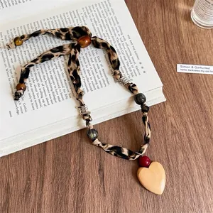 Dettaglio della collana in tessuto vintage con stampa leopardata, perle in legno e cuore