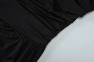 Close-up of black ruched fabric texture with fine pleats on an asymmetric dress