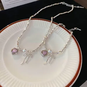 Silver necklace set with pink heart gemstone, white pearls and bow charm in a ceramic dish