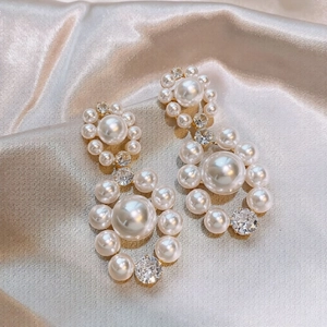 Elegant vintage pearl and zircon stud earrings on silk fabric background
