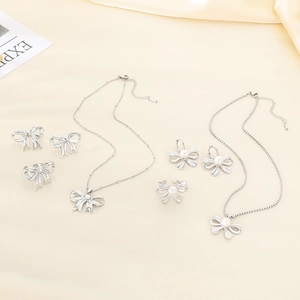 Elegant silver stainless steel bow jewelry set with pearls on soft beige silk