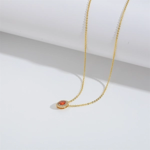 Detailed close-up of a gold necklace with a marquise red gemstone and zircon halo