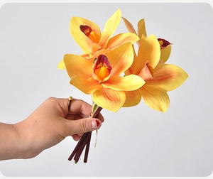Detail of hand-held 3D printed yellow artificial orchids with dark red core accents