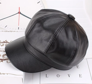 Detail view of black leather newsboy cap with textured finish and button top