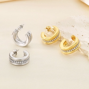 Detailed close-up of C-shaped earrings with gold and silver finish and zircon stones