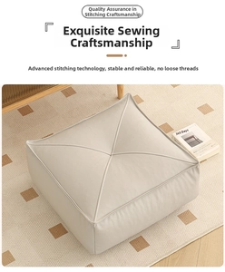 Detail of cross-stitched quilting on cream leather pouf ottoman at 45-degree angle
